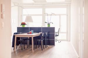 Vor dem Arbeitsplatz befindet sich, durch das System USM Haller räumlich getrennt, ein kleiner Besprechungstisch für vier Personen. Helle Farben mit viel Licht laden zum Gespräch ein.