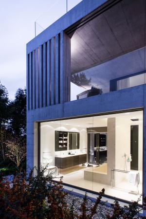 Bei dem modernen Neubau dominieren zwei Materialien: Beton und Glas. Große Fensterfronten sorgen für freie Sicht in alle Himmelsrichtungen. Die klaren Betonwände strukturieren das Gebäude. Passend zur modernen Architektur wurde das Haus mit Möbeln und Designklassikern eingerichtet, die auf das Wesentliche reduziert sind.