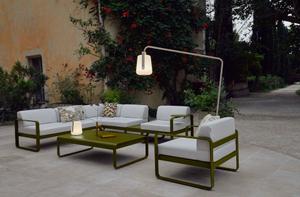 Elegante Fermob Outdoor-Möbelkollektion, einschließlich Balad Akkuleuchte, Bellevie Sofa mit versetztem Fuß, Alto Coffee Table, Tisch niedrig, Sessel und Beistelltisch in einem Garten
