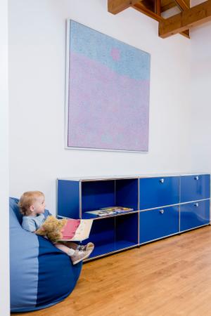 Das blaue Behandlungszimmer überzeugt mit Stauraum von USM Haller und bequemen Sitzmöbeln.