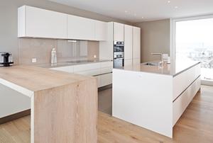 Die Küche Siematic S2 mit mit Lackfronten harmoniert mit dem Bodenbelag und der integierten Theke aus massivem Holz.