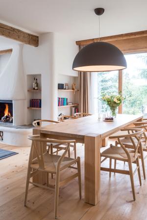 Treffpunkt Esszimmer: Der Holztisch Bigfoot von Philipp Mainzer, sowie die Wishbone Stühle von Carl Hansen unterstreichen den Landhaus Stil. Die Hängeleuchte Skygarden von Flos bildet einen schönen Gegensatz.