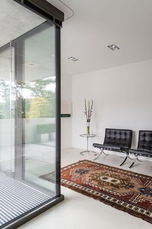 Im Eingangsbereich des modernen Hauses werden die Gäste empfangen. Sessel Barcelona von Knoll International, Beistelltisch Adjustable von Classicon, Design Eileen Gray.