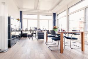 Die Arbeitsplatz und Besprechung sind in dem hellen Raum nebeneinander angeordnet und mit Systemmöbeln von USM Haller und Arbeitsstühlen von Vitra möbliert.